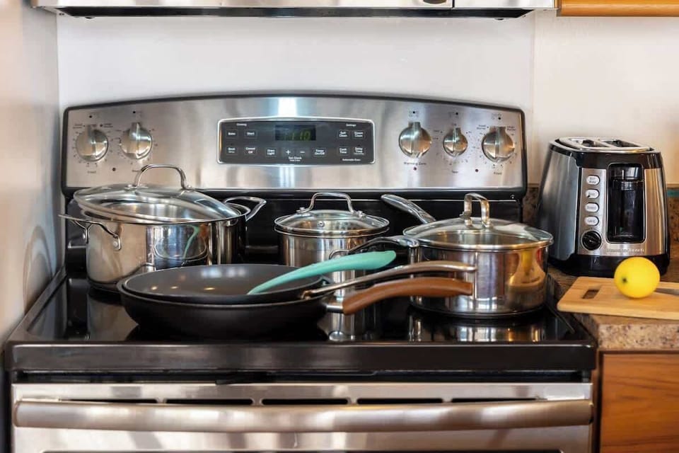 Easily prepare your favorite meals with the convenience of a well-stocked kitchen, featuring a modern stovetop and a selection of quality pots and pans ready for your culinary creations.