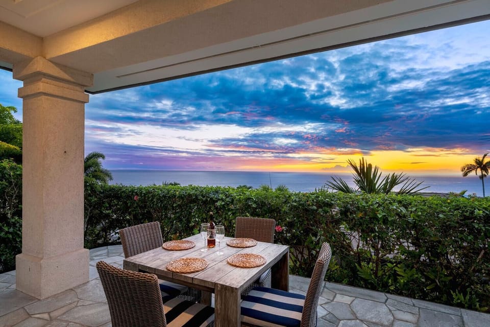 Private lanai seating outside the primary bedroom with sunset views over the Kona coast.