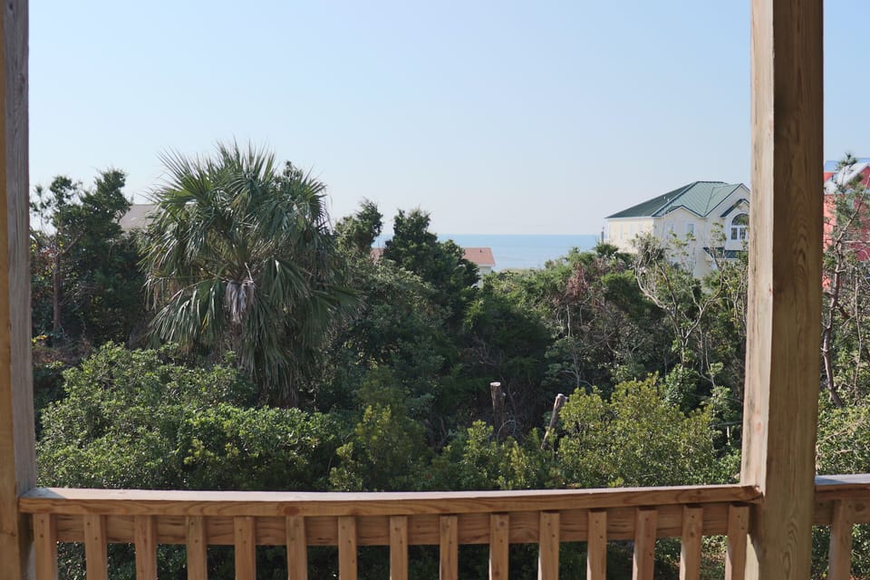Peaceful view through tropical foliage reveals glimpses of the distant coastline from your private balcony retreat.