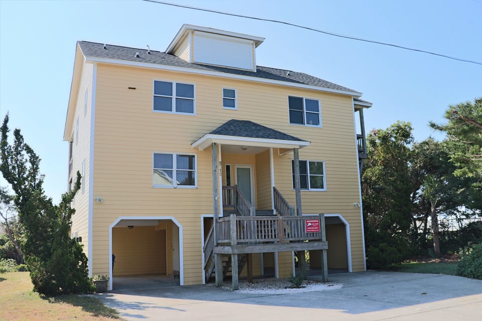 Charming beach house with elevated design and covered parking, nestled among coastal trees for a perfect getaway retreat.