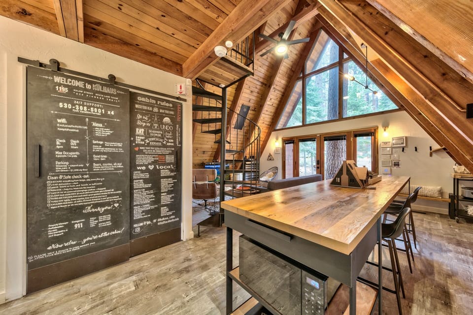 Step into your rustic-modern cabin featuring soaring wood beams, a spacious kitchen island, and spiral stairs leading to your cozy loft retreat.