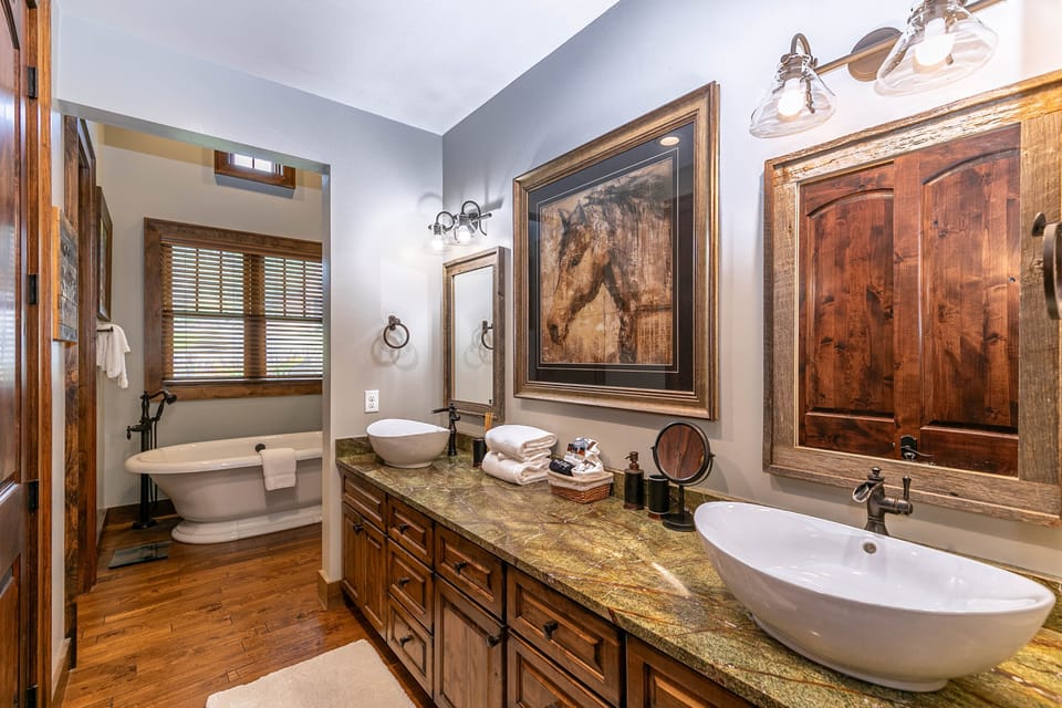 Rustic elegance meets spa comfort. Double vessel sinks, a freestanding soaking tub, and rich wood details set the tone at Prancing Horse Lodge At Eagles Nest.