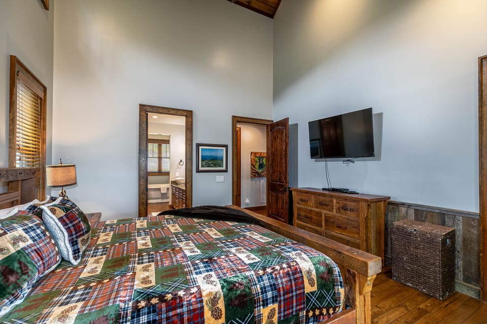 Cozy mountain nights await in this spacious master suite with rustic wood accents and a plaid quilt made for the Blue Ridge.