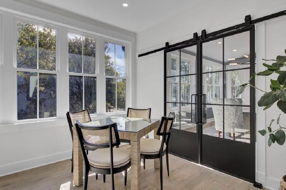 - Intimate dining nook surrounded by windows and bathed in natural light - Glass top table with rattan style chairs makes a charming morning spot - Sliding barn doors open to the dining room for added space or privacy
