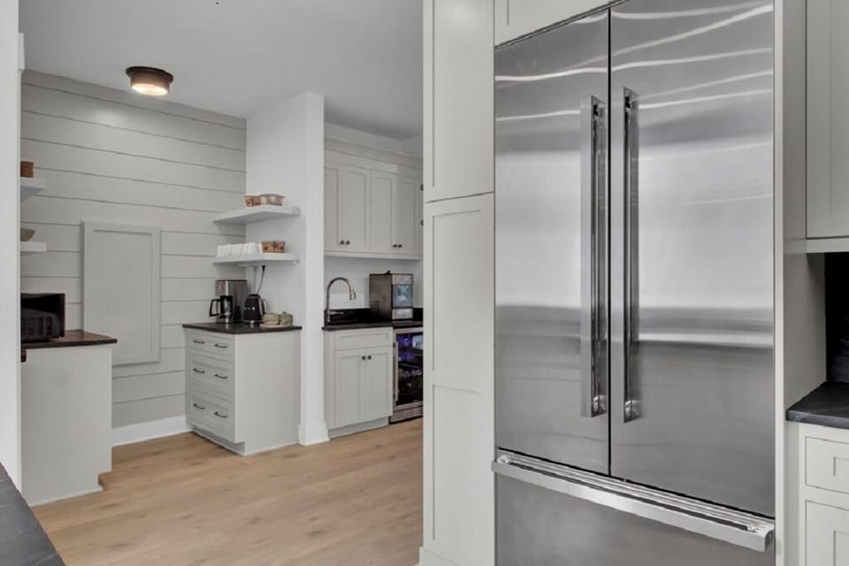 - Convenient nook with coffee maker, ice machine, and built in microwave for easy access - Stylish cabinetry and wood shelving offer both charm and practicality - Stainless steel fridge and black counters round out the polished design