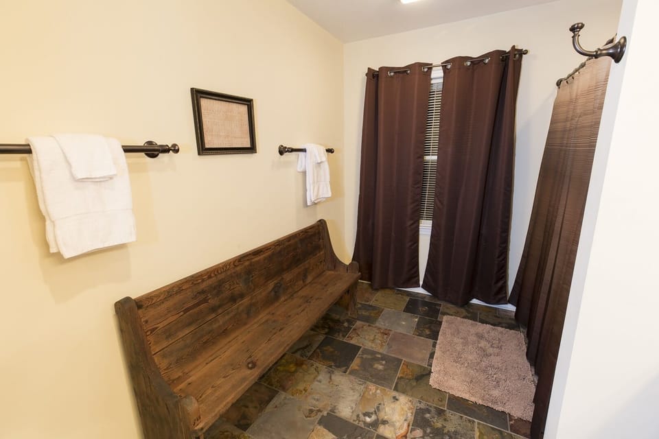 This shared bathroom is complete with an antique church pew.