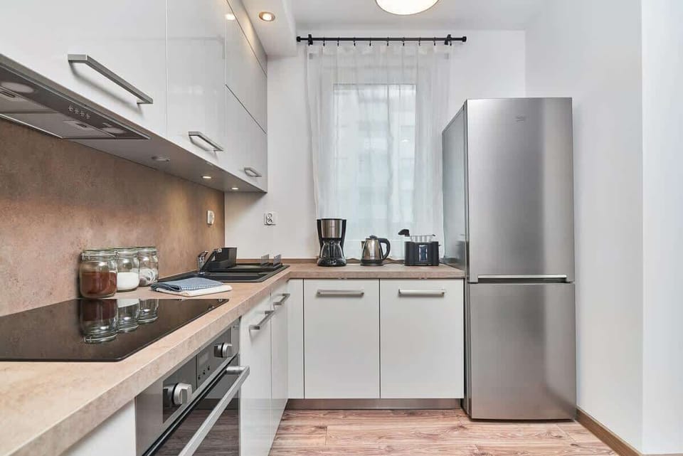 Kitchenette with white cabinets. A large fridge freezer can be seen opposite.