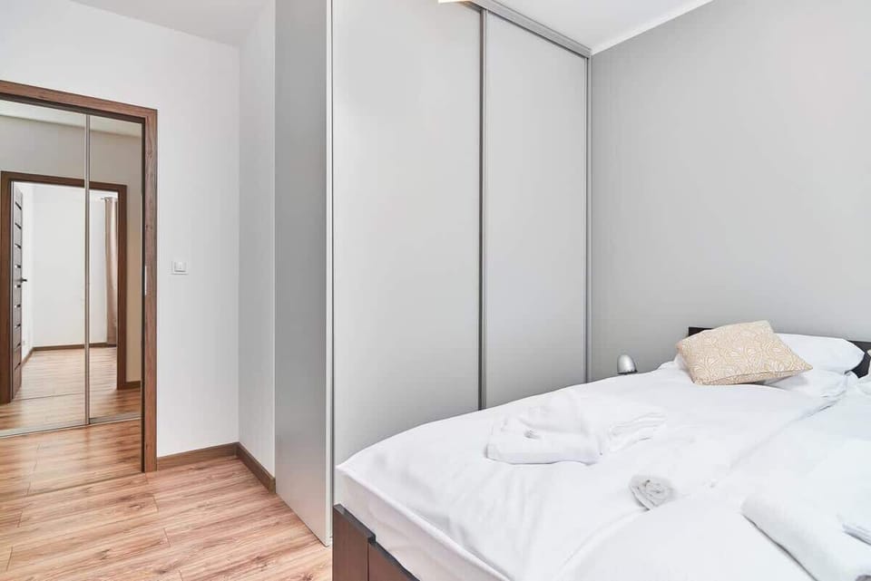 Bedroom with a double bed, white linens, and modern decor including a wardrobe and mirror.