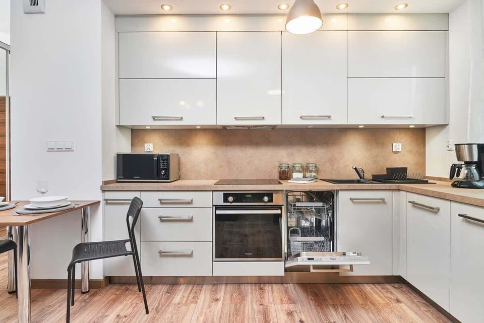 A spacious kitchen with white cabinets, integrated appliances, a wooden countertop, and a dining table.