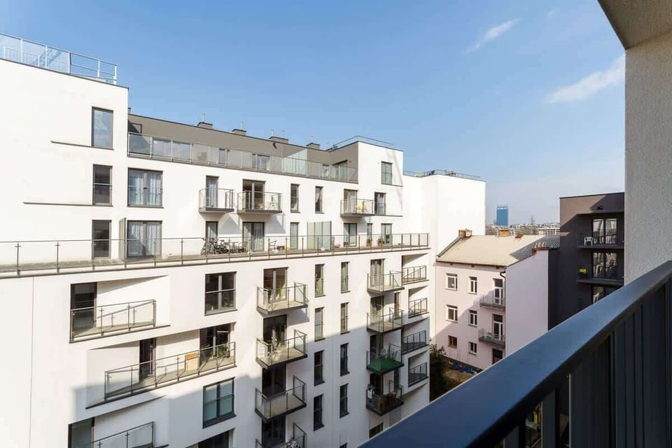 A balcony view overlooking a courtyard and neighboring modern buildings.