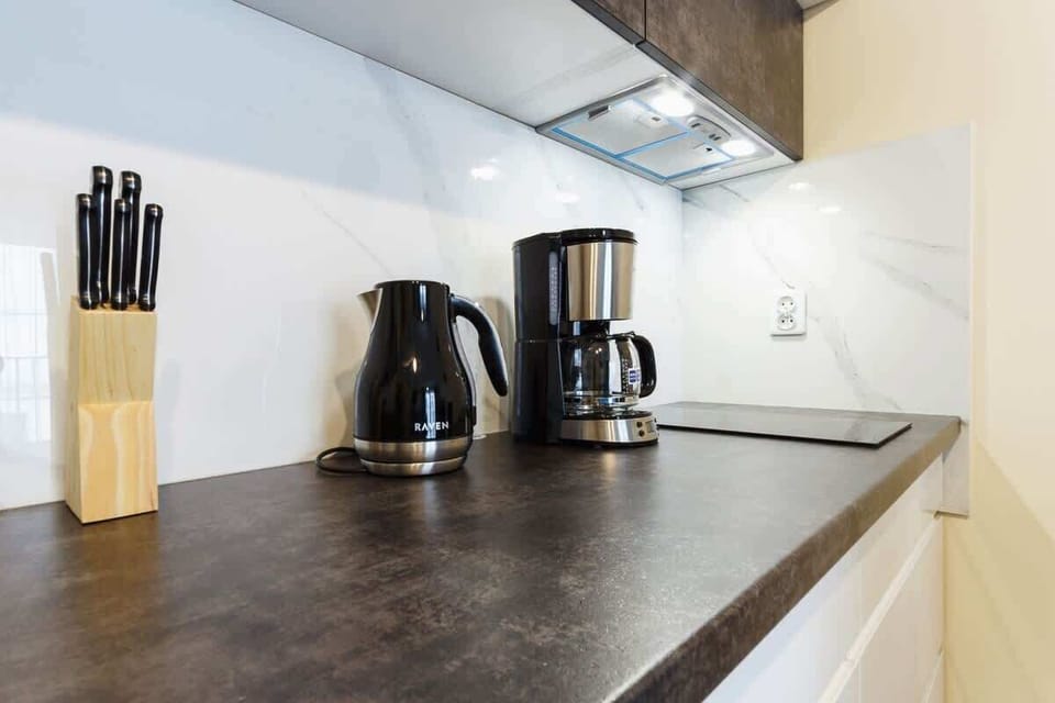 Close-up of the electric kettle and coffee machine on the dark countertop in the kitchenette. 