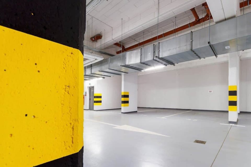 A secure underground parking space with clearly marked zones and bold yellow-and-black pillars for safety and visibility.