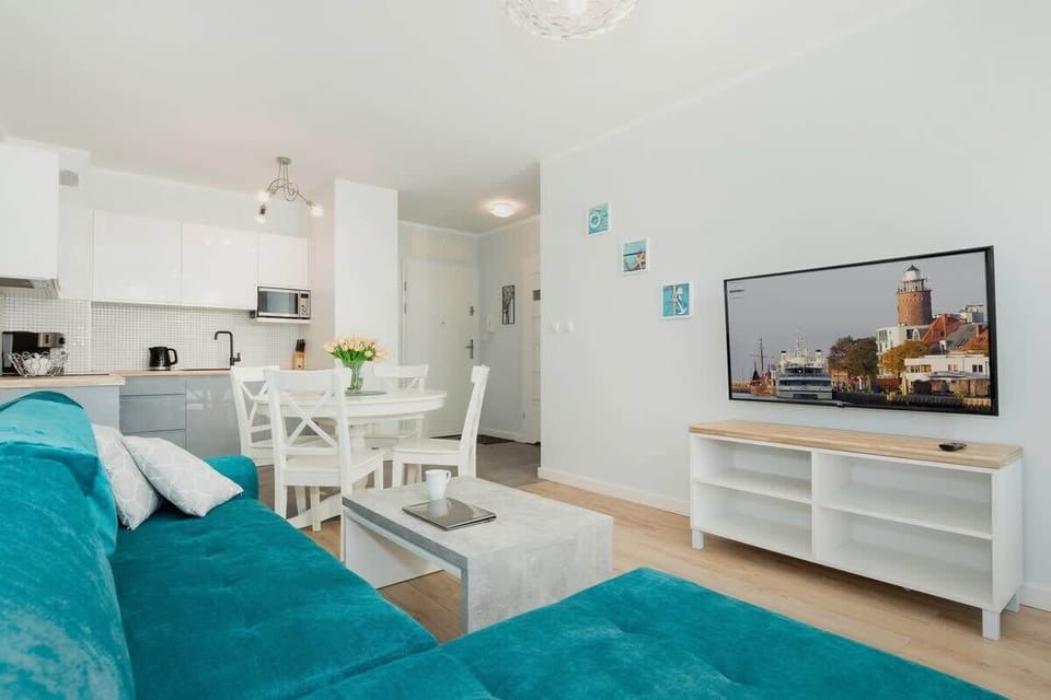 A view of the sofa and large TV, with the kitchenette visible in the background. 