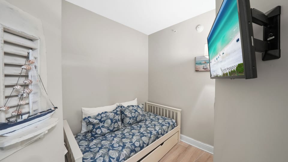 Your cozy bedroom features beach-themed décor and a wall-mounted TV for relaxation after sunny days exploring.
