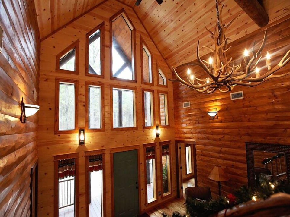 Soaring vaulted ceilings and a wall of windows fill this warm, wood-lined great room with natural light and cozy cabin charm.
