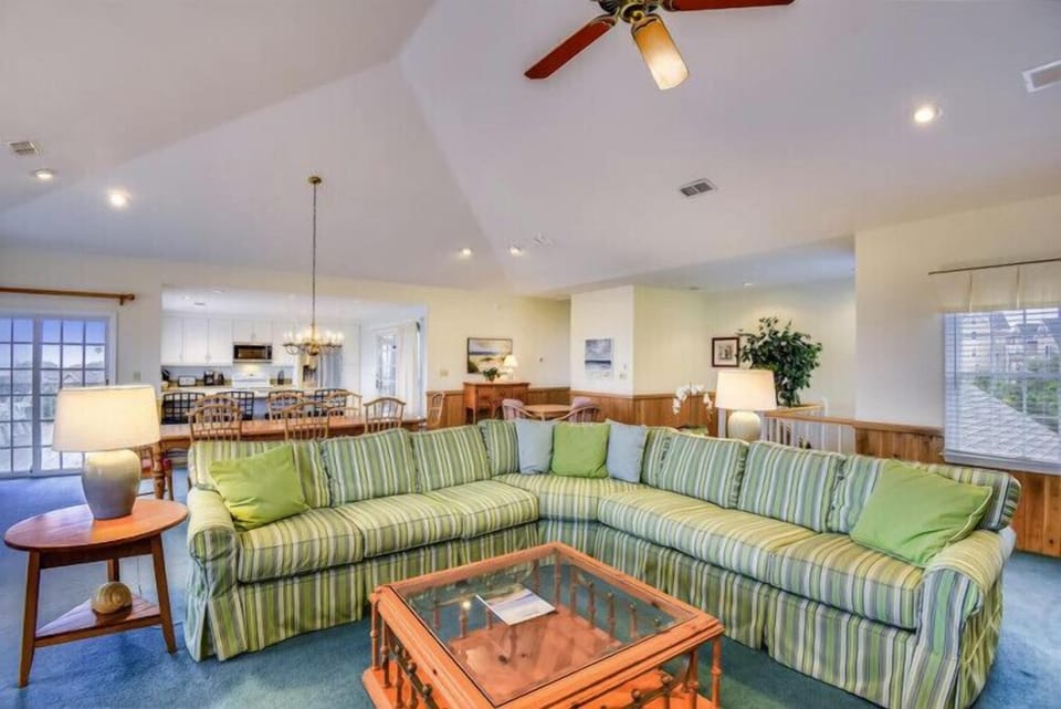 Settle into this bright, open living space where vaulted ceilings and natural light create an airy retreat. Relax on the spacious sectional, gather around the dining area, or step out onto your private terrace—your home away from home awaits.