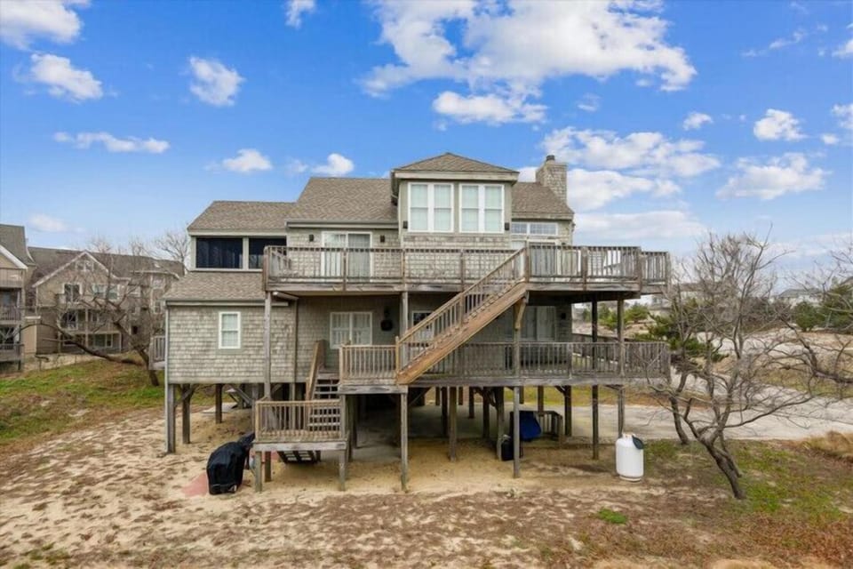 A coastal getaway elevated on stilts with expansive deck space and direct beach access, situated in a peaceful seaside community.