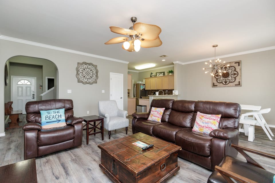 Relax in your spacious open-concept living area with plush leather seating, tropical ceiling fan, and seamless flow to the fully equipped kitchen.