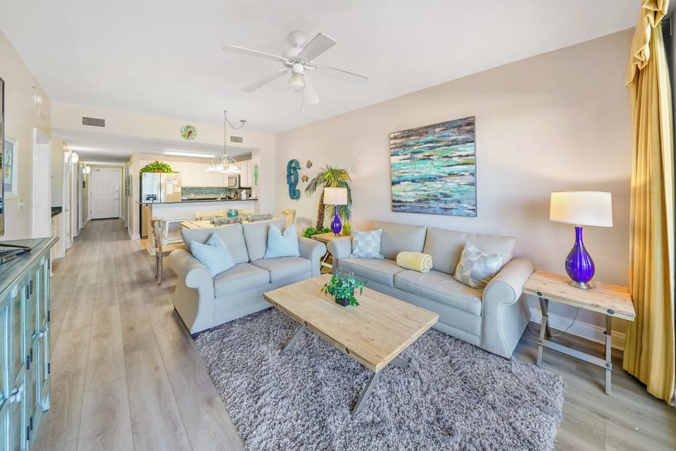 Sink into plush sofas in this bright, open living space where coastal blues meet warm wood tones, creating your perfect retreat.