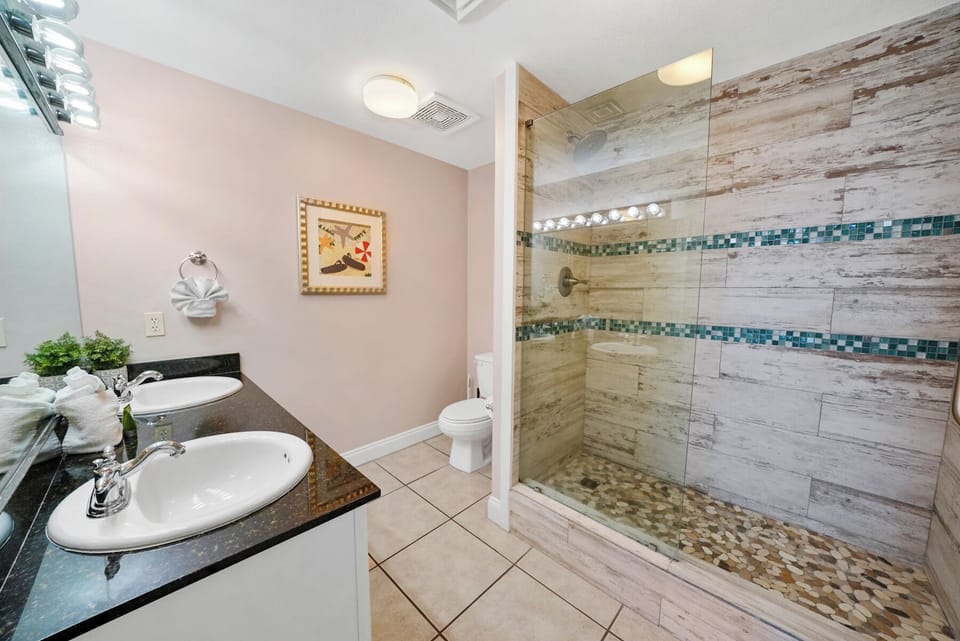 Indulge in your private spa-like bathroom featuring a stunning glass-enclosed shower with mosaic tile accents and pebbled flooring.