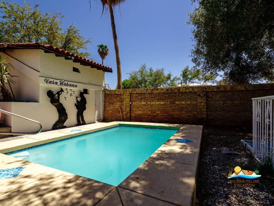 See the modern pool from the side at Casa Habana in San Felipe Baja California — lounging area and ocean backdrop.