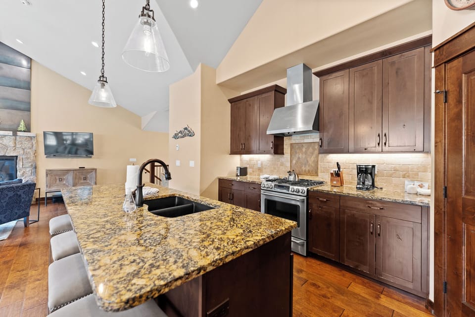 The full kitchen features granite countertops, stainless steel appliances, a wine fridge, and breakfast bar seating for 4.