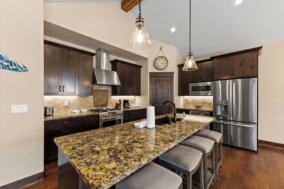 The full kitchen features granite countertops, stainless steel appliances, a wine fridge, and breakfast bar seating for 4.