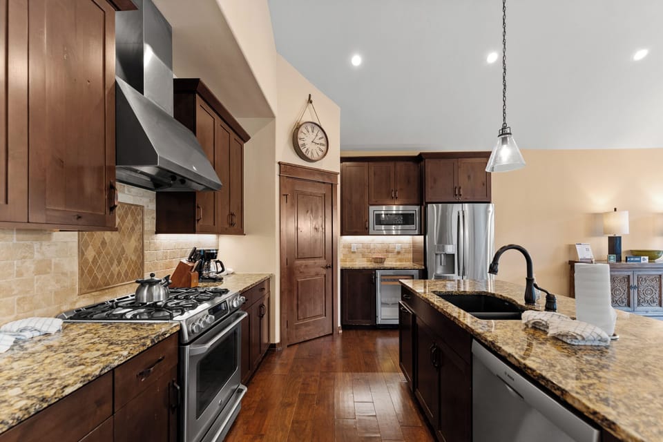 The full kitchen features granite countertops, stainless steel appliances, a wine fridge, and breakfast bar seating for 4.