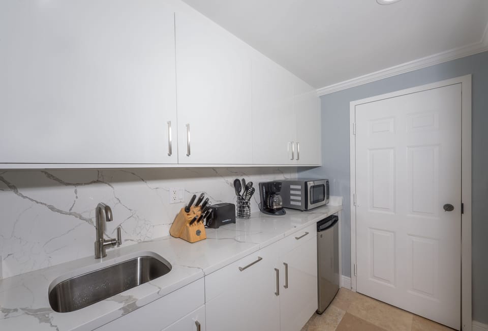 Kitchenette with fridge, microwave, coffee maker, toaster, blender, & sink.