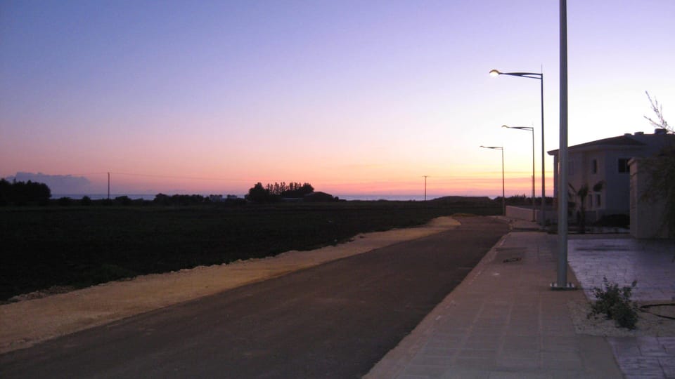 Road outside front of apartment, overlooking fields with sea on horizon