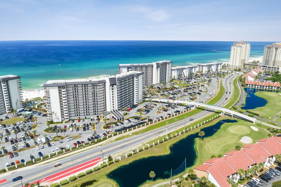 Aerial view of beachfront resort property with direct beach access, surrounded by golf course and coastal landscape along the Gulf Shore.