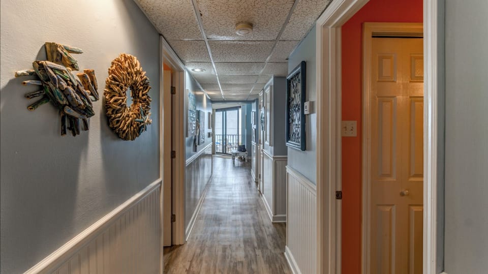 Stroll through your beautifully appointed hallway, where nautical wreaths and coastal artwork create a welcoming seaside atmosphere leading to your bright oceanfront retreat.
