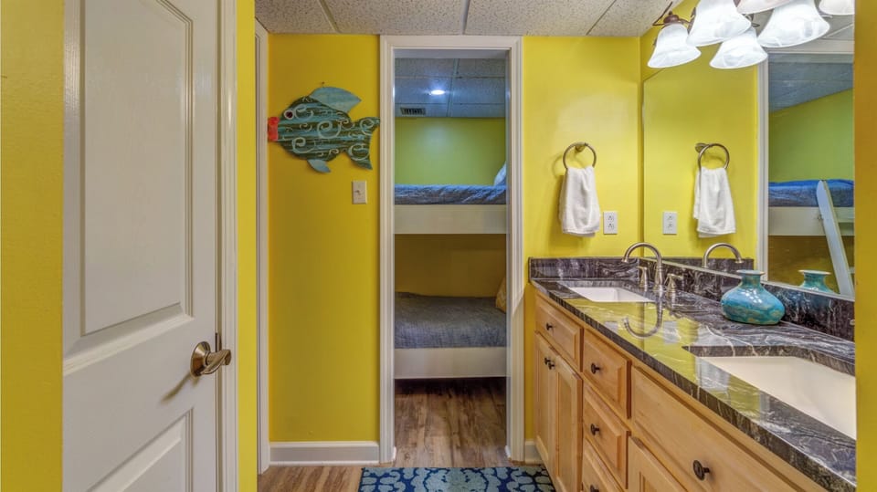 Your bright bathroom features double sinks with granite countertops, convenient storage, and cheerful yellow walls that create a welcoming morning routine.