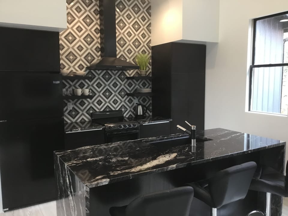 Full service kitchen with granite waterfall island and barstools