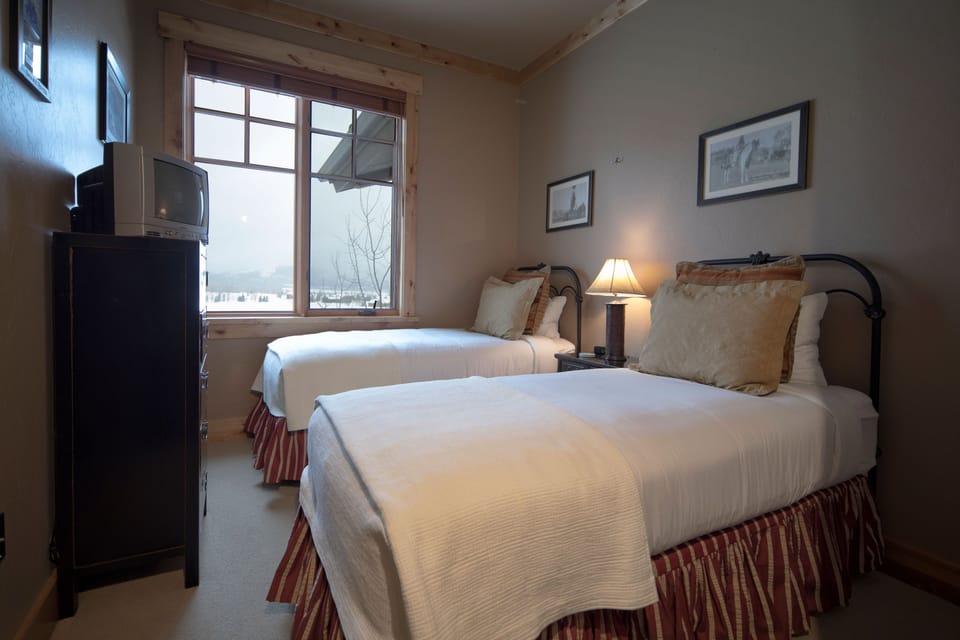 Rest peacefully in your cozy twin bedroom where rustic wooden beams meet modern comfort. Wake up to serene winter views through your window while staying warm and connected with your own TV.