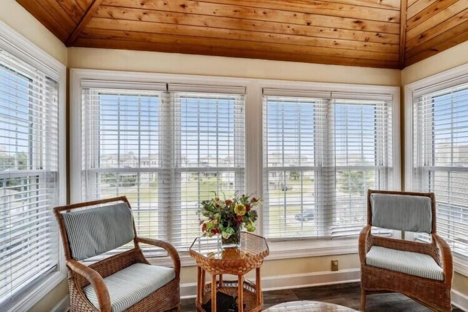 Settle into your peaceful sunroom retreat, where natural light streams through expansive windows and a cozy seating area invites you to unwind with views of the surrounding landscape.