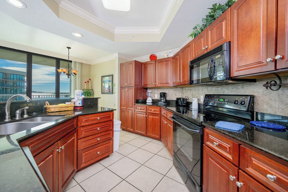 Prepare meals in this kitchen with elegant cabinetry, black appliances, and spacious countertops