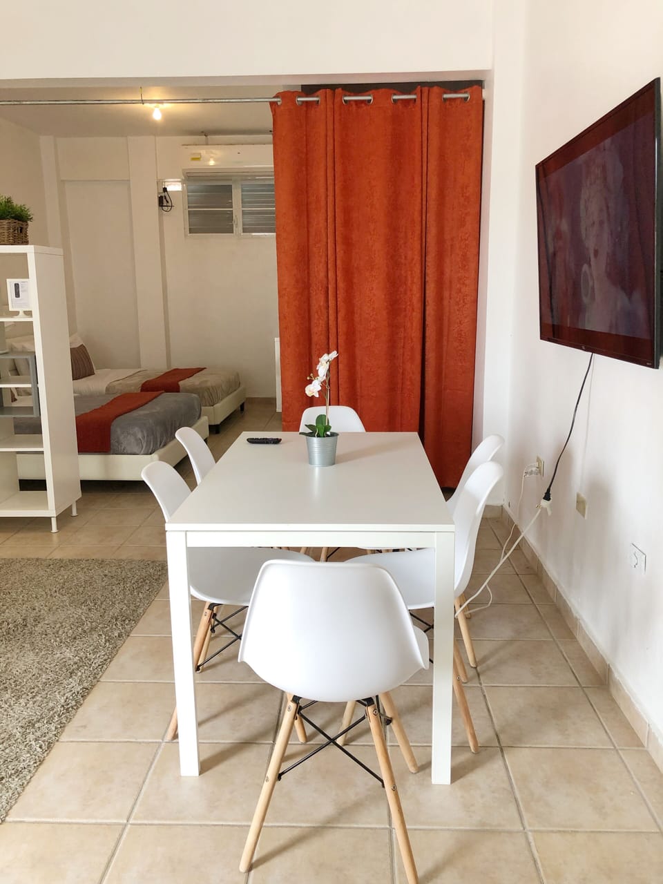 Area de comedor con 6 sillas, smart TV y esta proximo al area de cocina.