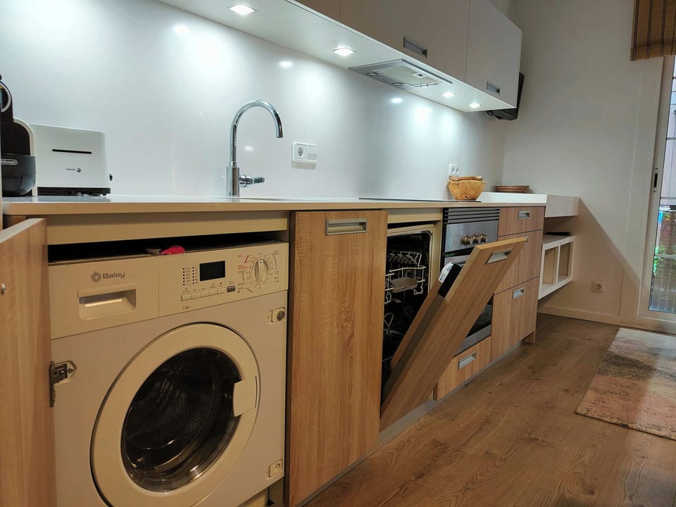 The loft's kitchen boasts a modern design with sleek white cabinets and wood accents. It is fully equipped with a dishwasher, oven, microwave, toaster, fridge, and coffee maker. The kitchen also includes a washing machine for your convenience. The wood fl