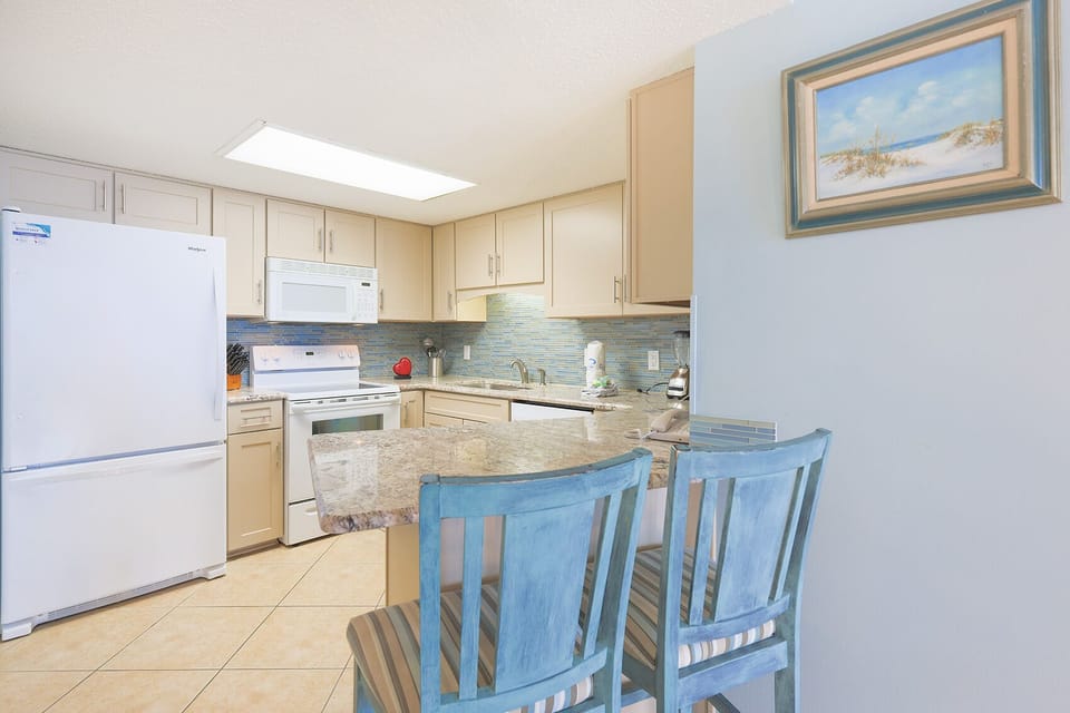 Enjoy meals at the breakfast bar, surrounded by a stylish kitchen featuring white appliances and vibrant decor