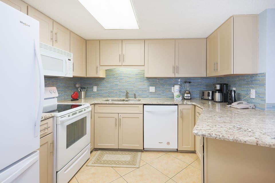 Enjoy cooking in this kitchen, featuring granite counters, white appliances, and a stylish backsplash