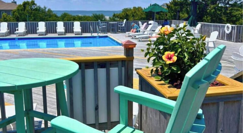 Relax poolside with vibrant blooms and coastal breezes—your sunny retreat awaits with loungers, umbrellas, and serene sea views beyond.