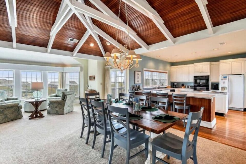Step into a stunning open-concept living space where dramatic vaulted wood ceilings and natural light create a warm, inviting atmosphere for your coastal getaway. You'll love cooking and dining together in this beautifully designed retreat.