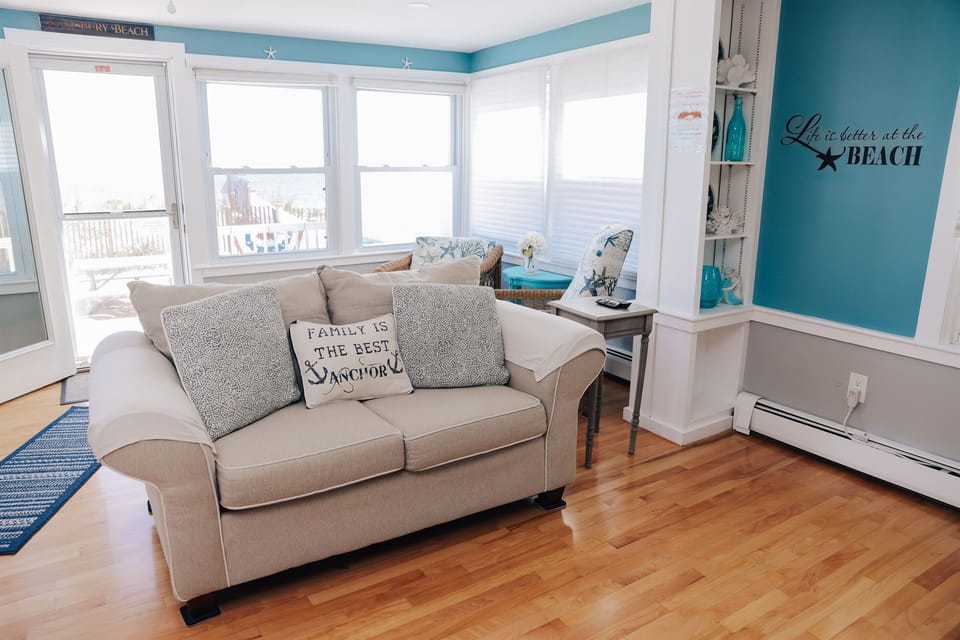Spacious oceanfront living room with comfortable seating, perfect for relaxing after a day at Salisbury Beach while enjoying coastal views and natural light.