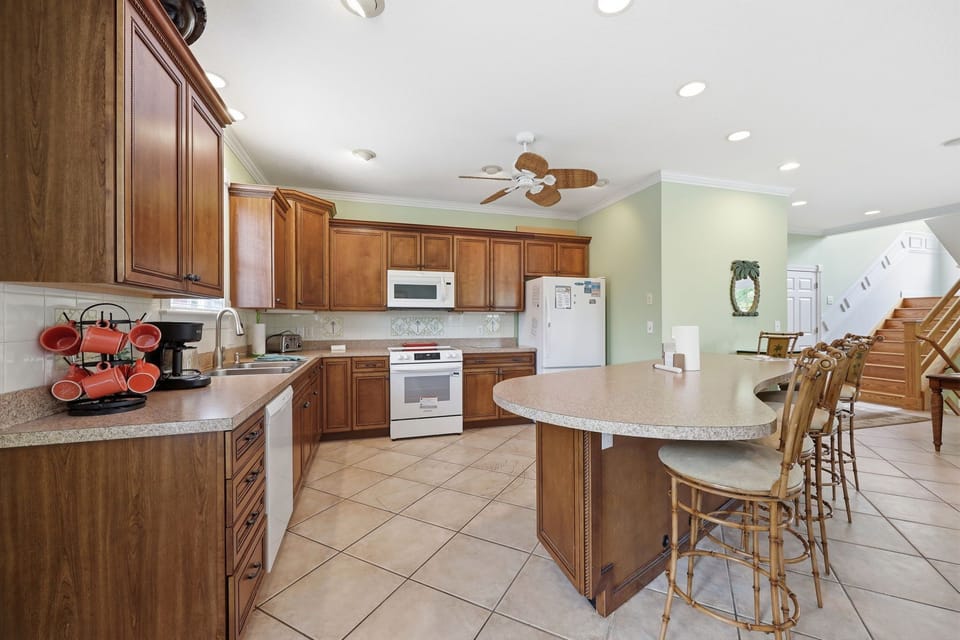 Picture yourself preparing meals in this spacious kitchen with warm wood cabinetry, granite counters, and a welcoming island with seating—perfect for morning coffee or gathering with loved ones.