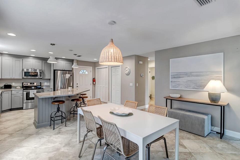 - Open kitchen and dining layout with stainless steel appliances and sleek cabinetry
- Spacious island bar with rustic stools invites group gatherings and casual meals
- Rattan lighting and coastal decor add warmth and charm throughout the space