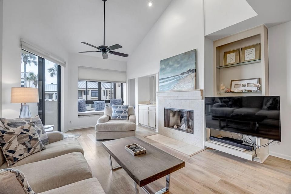 - Stylish living room with vaulted ceilings, cozy fireplace, and mounted TV
- Large windows let in natural light and offer relaxing views of the outdoors
- Plush sofas and modern décor create the perfect spot for lounging or reading