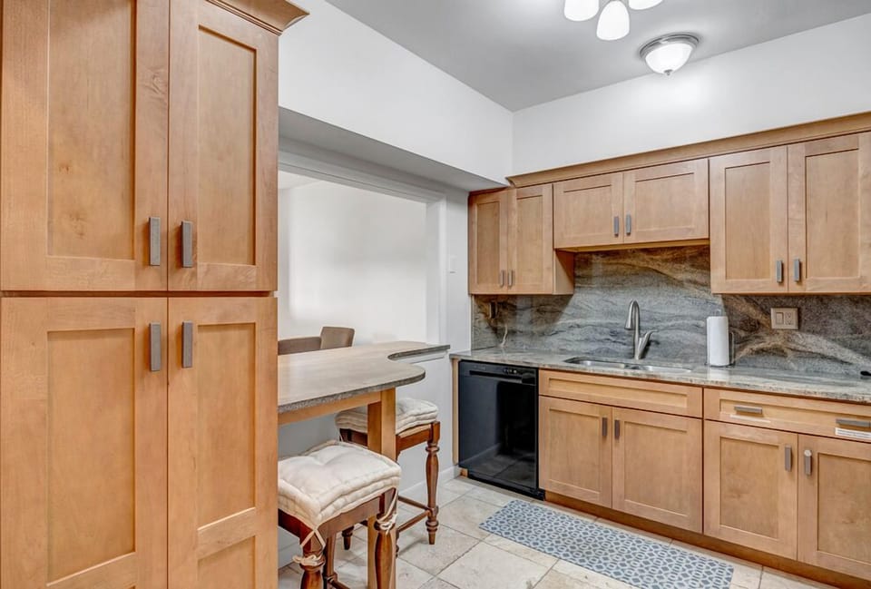 - Cozy breakfast bar pairs with tall cabinetry and sleek granite backsplash
- Pull up stools make for casual dining or a quiet morning coffee nook
- Thoughtfully designed for comfort, storage, and functionality in one space