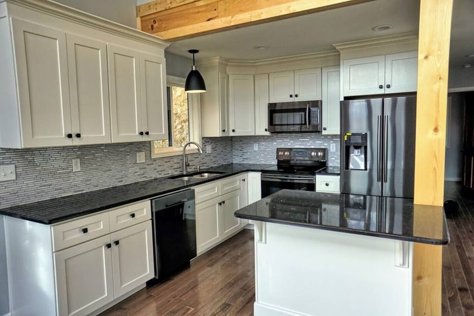 Modern full-size kitchen equipped with everything you may need, featuring granite countertops and a small island with barstool seating — perfect for cooking, dining, and gathering.