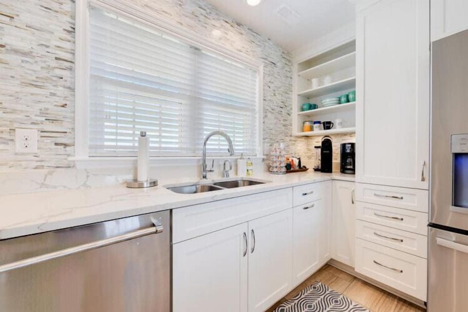 A bright, modern kitchen awaits you with stylish marble countertops, stainless steel appliances, and coffee-making essentials ready for your morning routine.
